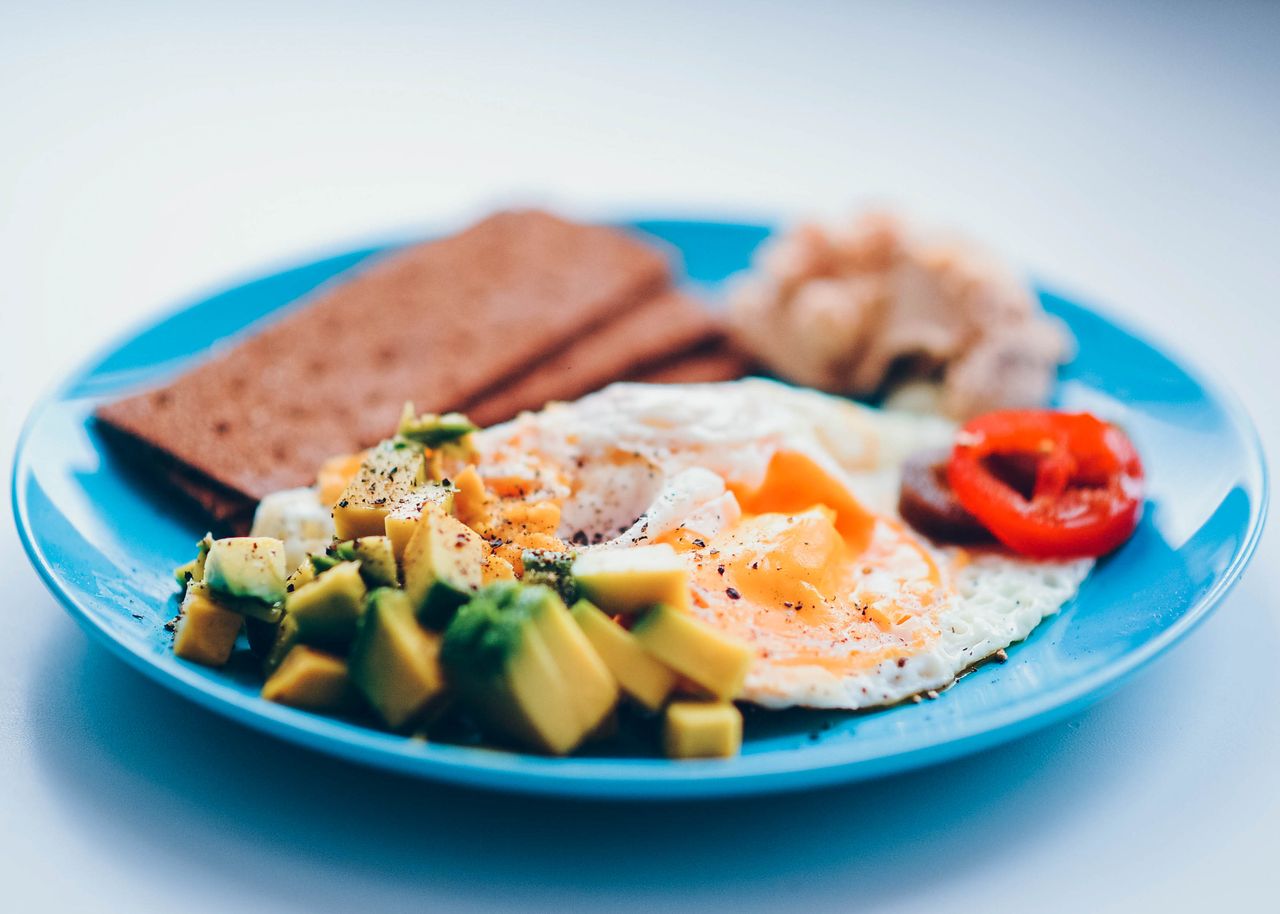 Crafting Captivating Headlines: Your awesome post title goes here Bright and colorful breakfast featuring fried eggs, avocado, and fresh vegetables on a blue plate.