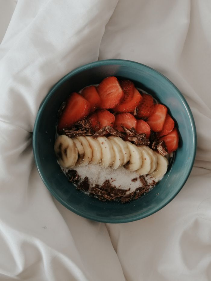 Offerings A delicious homemade breakfast bowl with fruits and chocolate on a cozy setting.