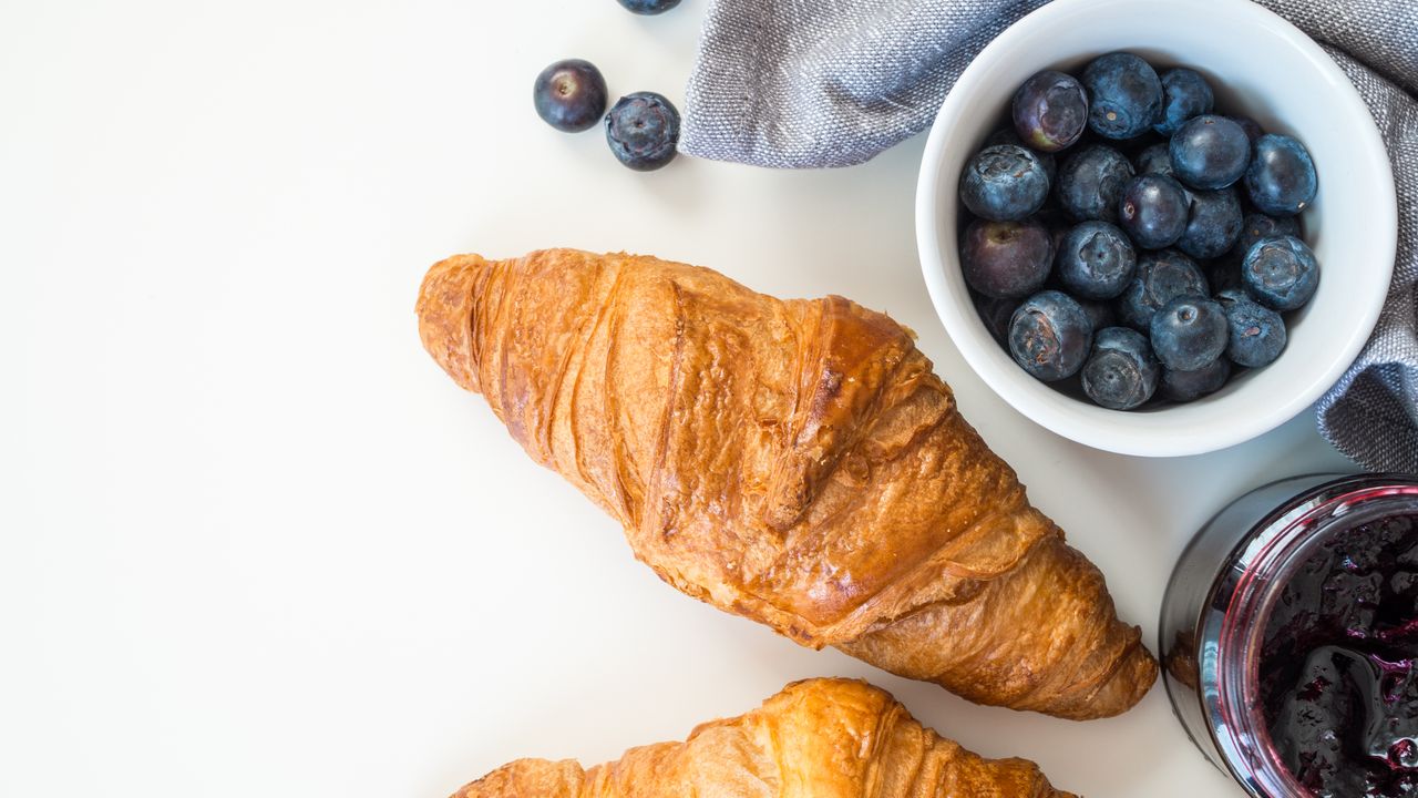 Home A tempting French breakfast featuring croissants, fresh blueberries, and jam, perfect for a healthy start.
